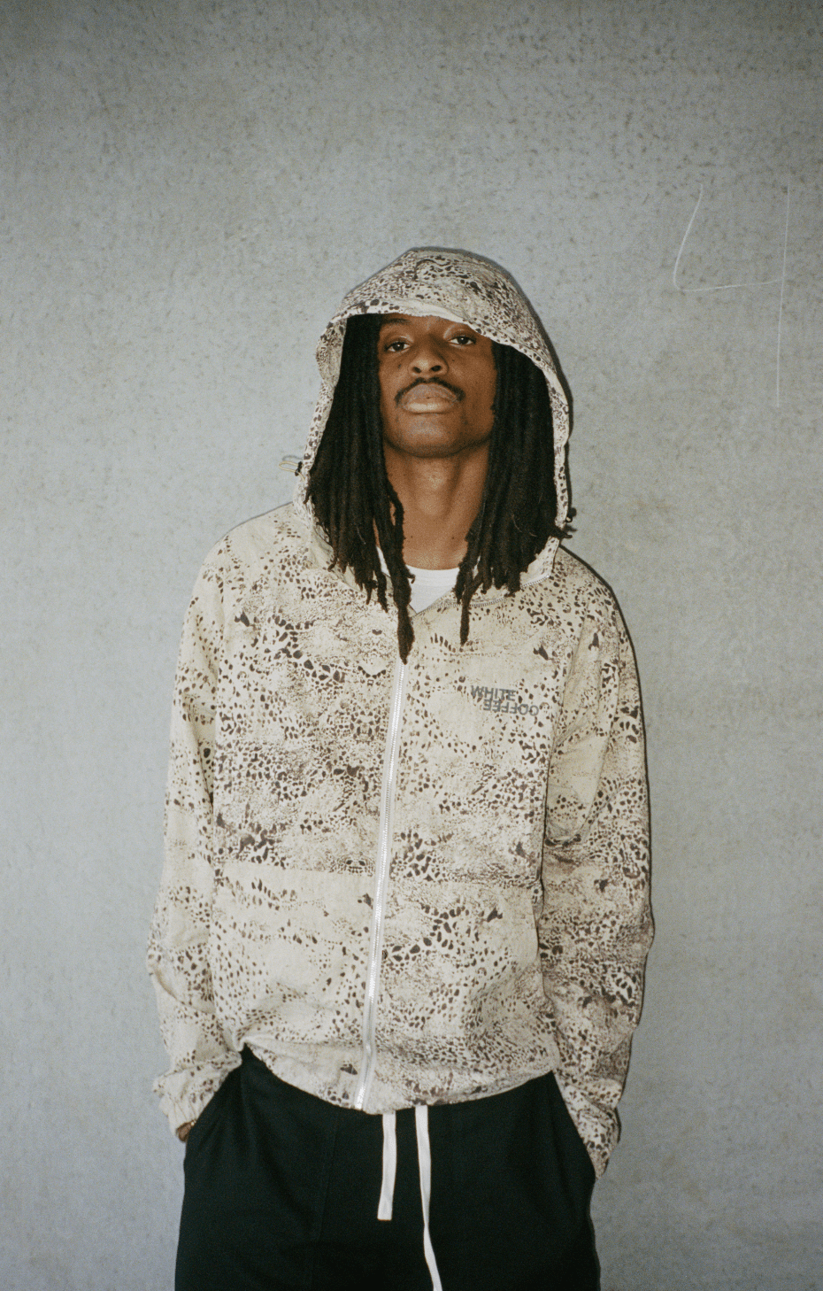 Beige digital print windbreaker with drawstring hood and front zipper, worn