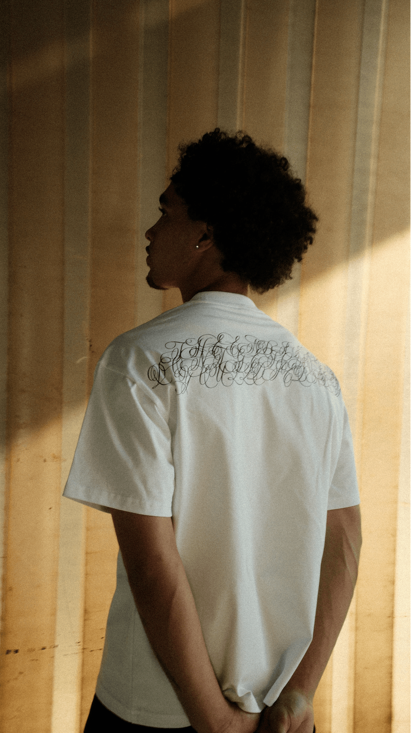 Light-colored script T-shirt with large back graphic, model back view