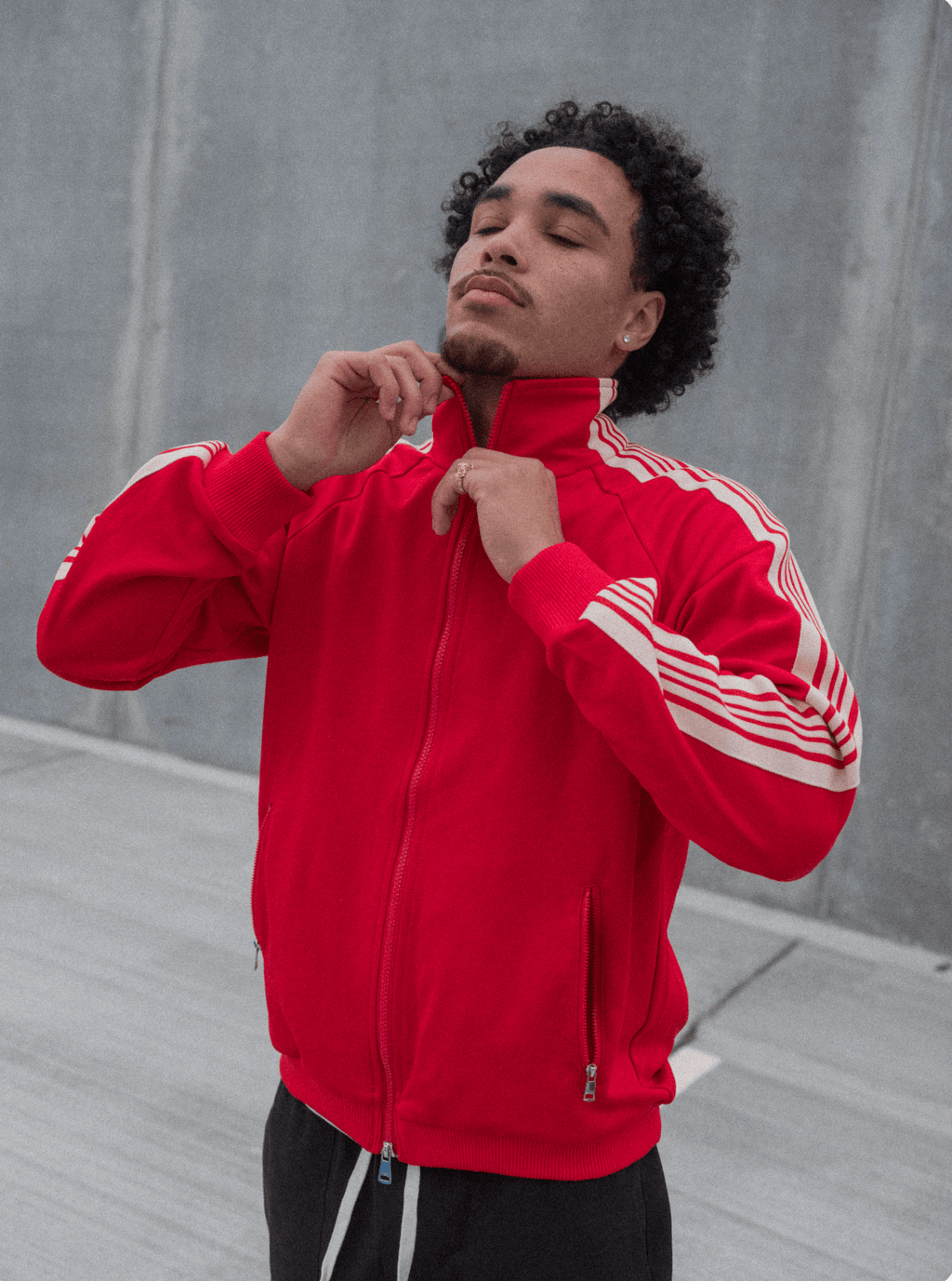 Red track jacket close-up with white sleeve and shoulder stripes, full-zip front